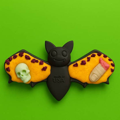 Black Bat nylon chew toy spread with orange treats on a green background
