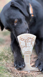 Black dog sniffing a white stone object on grass