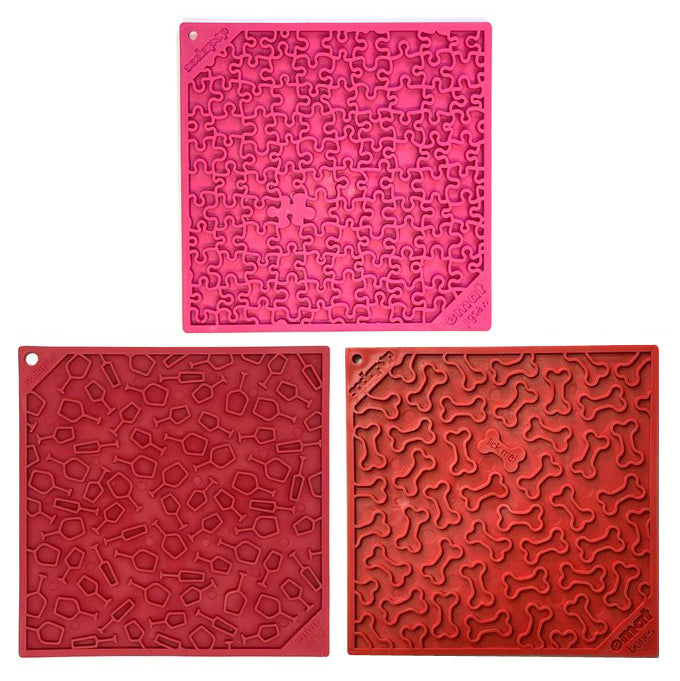 Three square licking mats in pink, and red,  each featuring a unique embossed pattern, arranged on a plain white background.